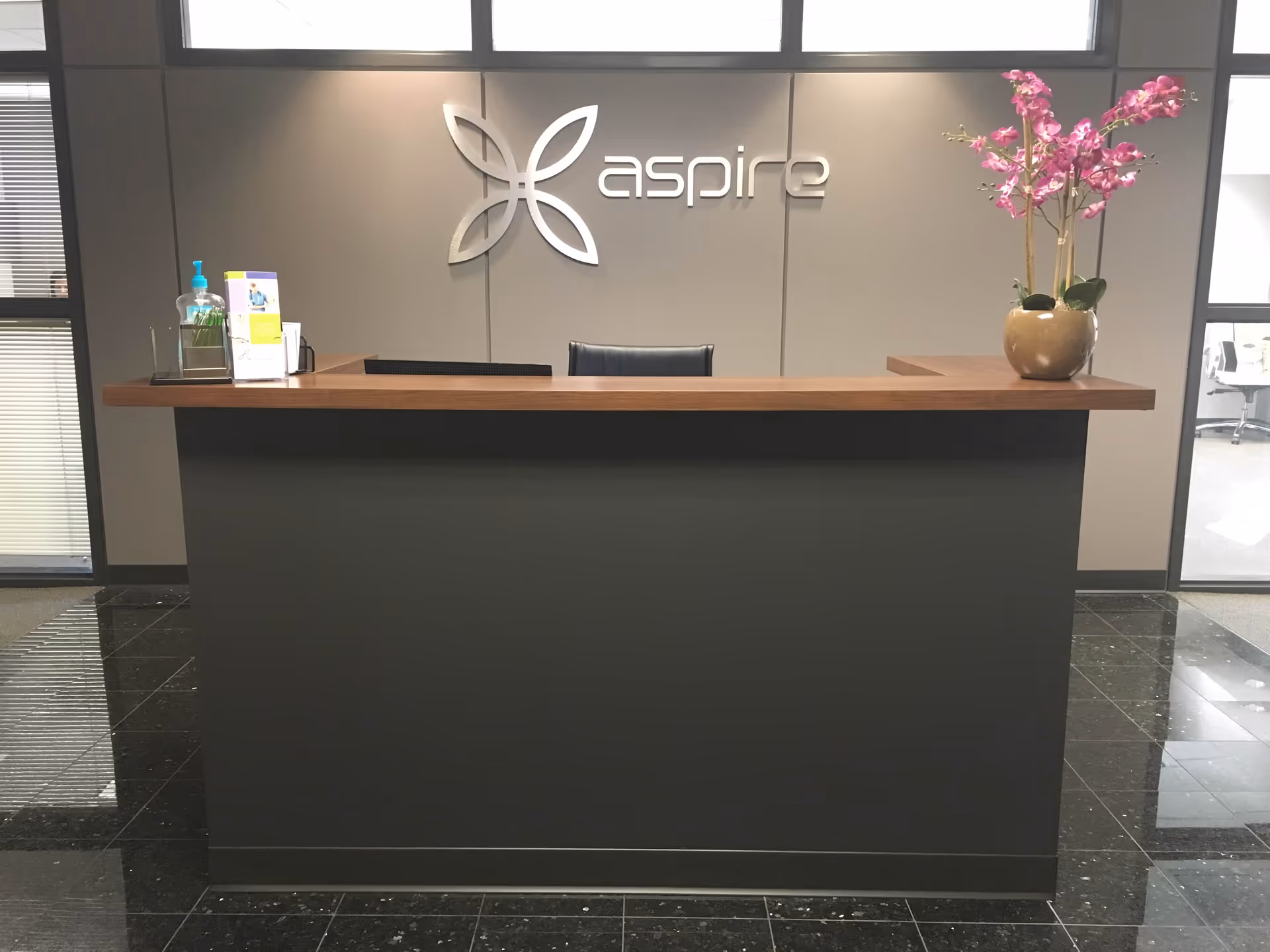 Modern reception desk in Aspire facility lobby with a potted flower arrangement.