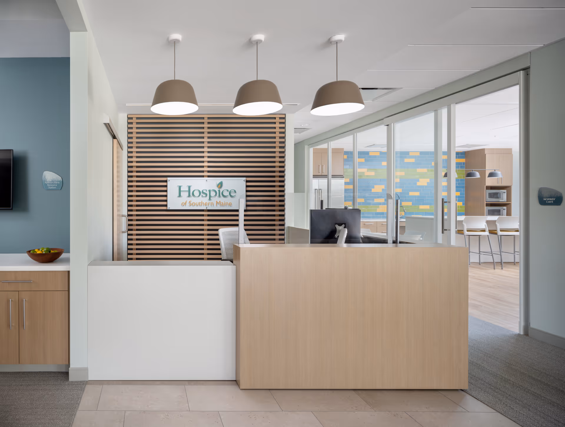 Modern reception area with a wooden desk, sign, and glass-walled corridor.