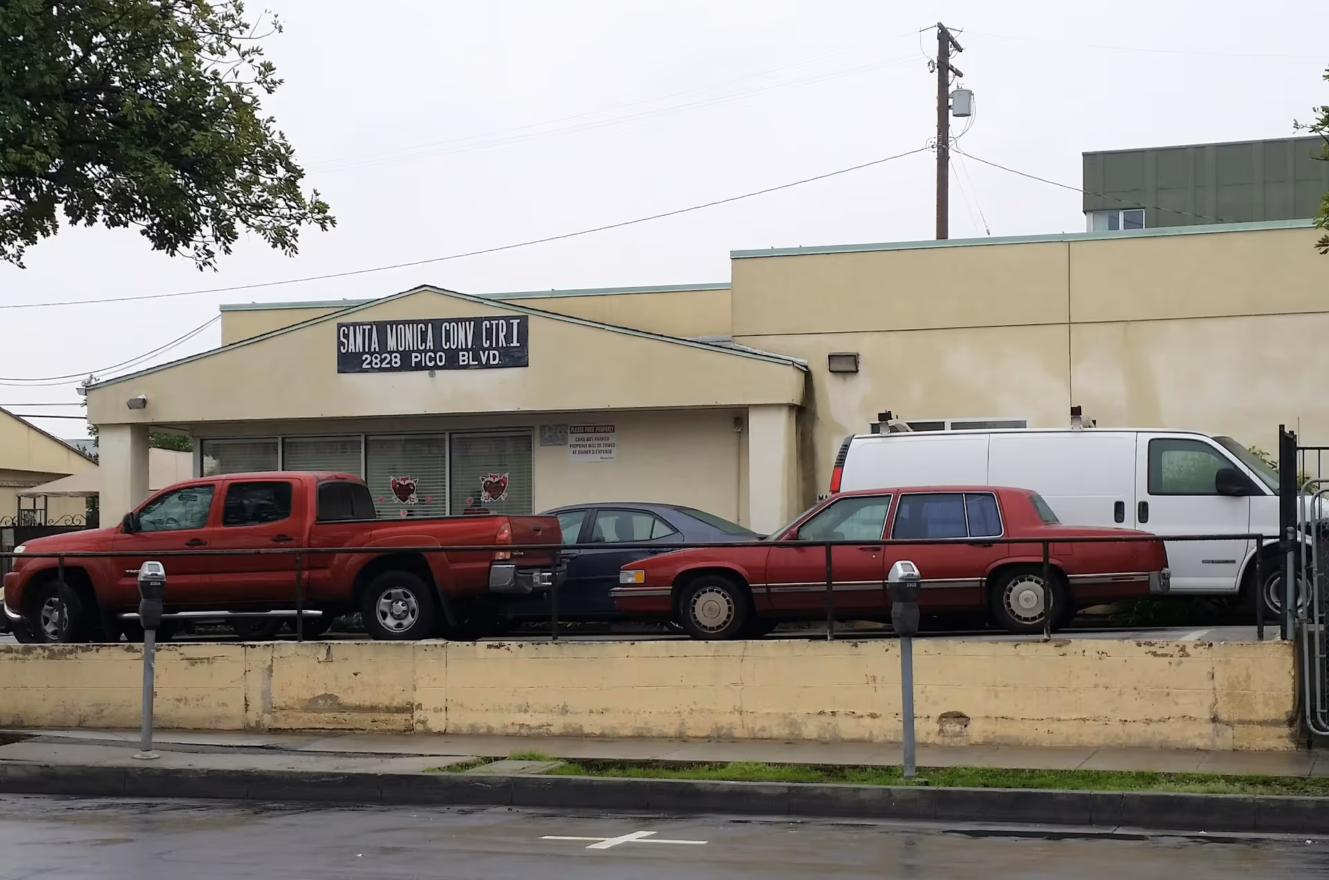 Beige facility building with Santa Monica Conv Center sign and parked red trucks.