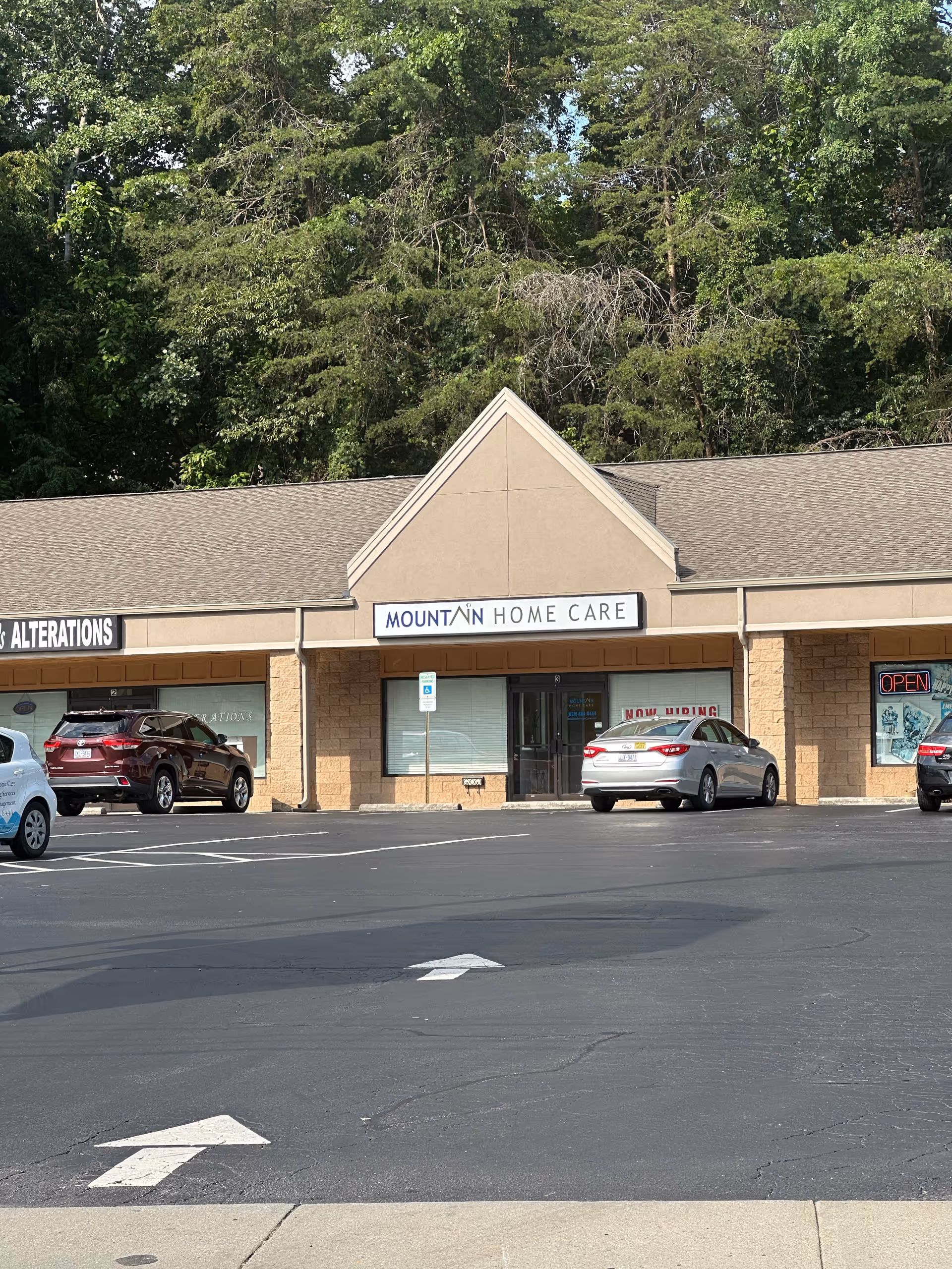 Front view of Mountain Home Care storefront with parked cars and trees behind.