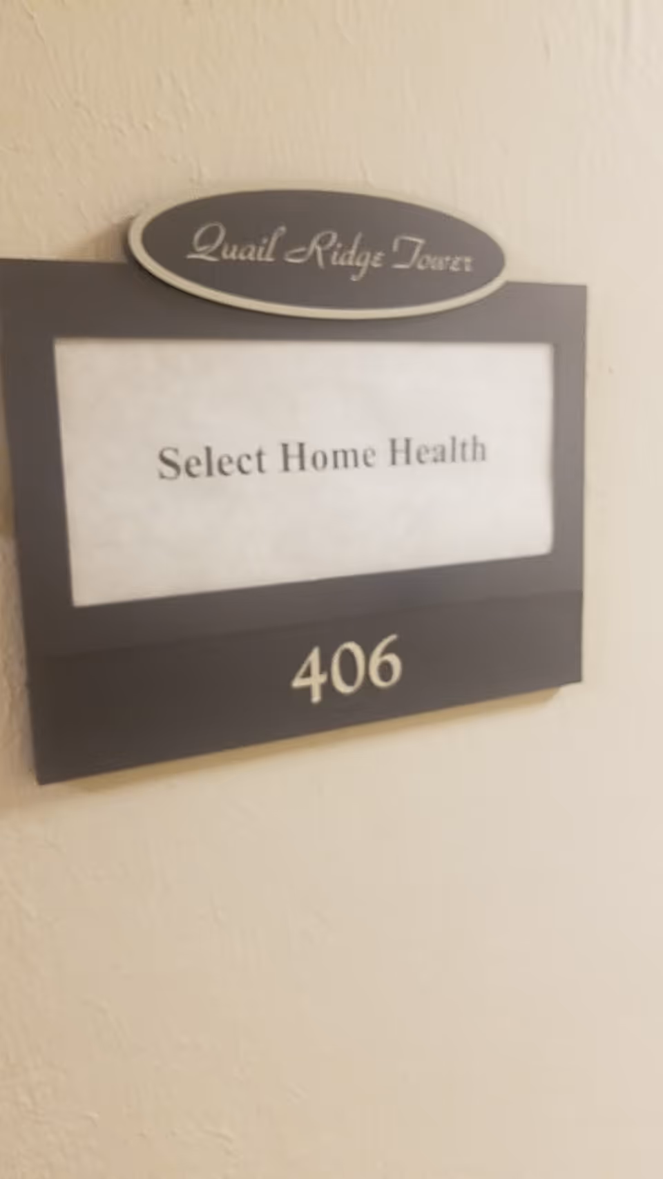 Interior hallway sign displaying Quail Ridge Tower, Select Home Health, and room 406.