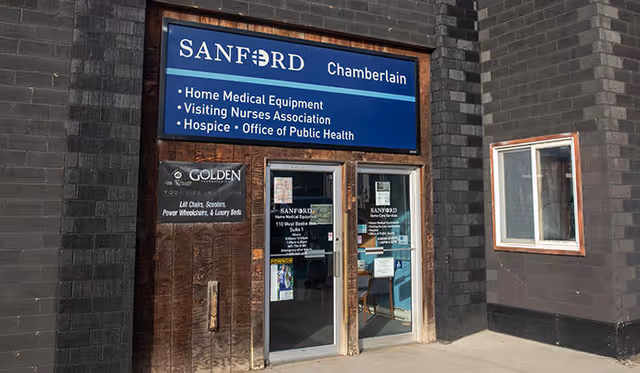 Front entrance of Sanford Home Health Chamberlain building with blue sign and glass doors.