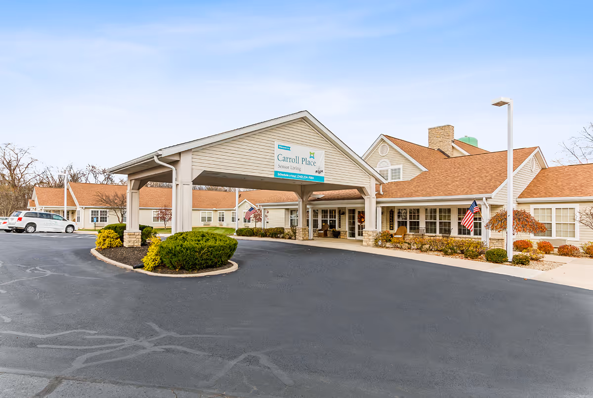 Exterior view of Carroll Place senior living facility with a covered entrance and parking lot.