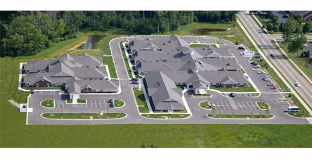 Aerial view of The Willows at East Lansing, showing connected buildings, parking lots, and green space.