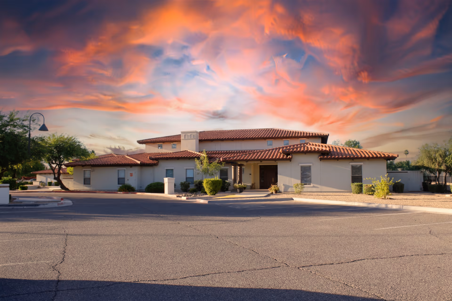 Senior living facility exterior with terracotta roof under a colorful sunset.