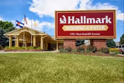 Exterior view of Hallmark Nursing Center with a red sign, flags, and manicured lawn.