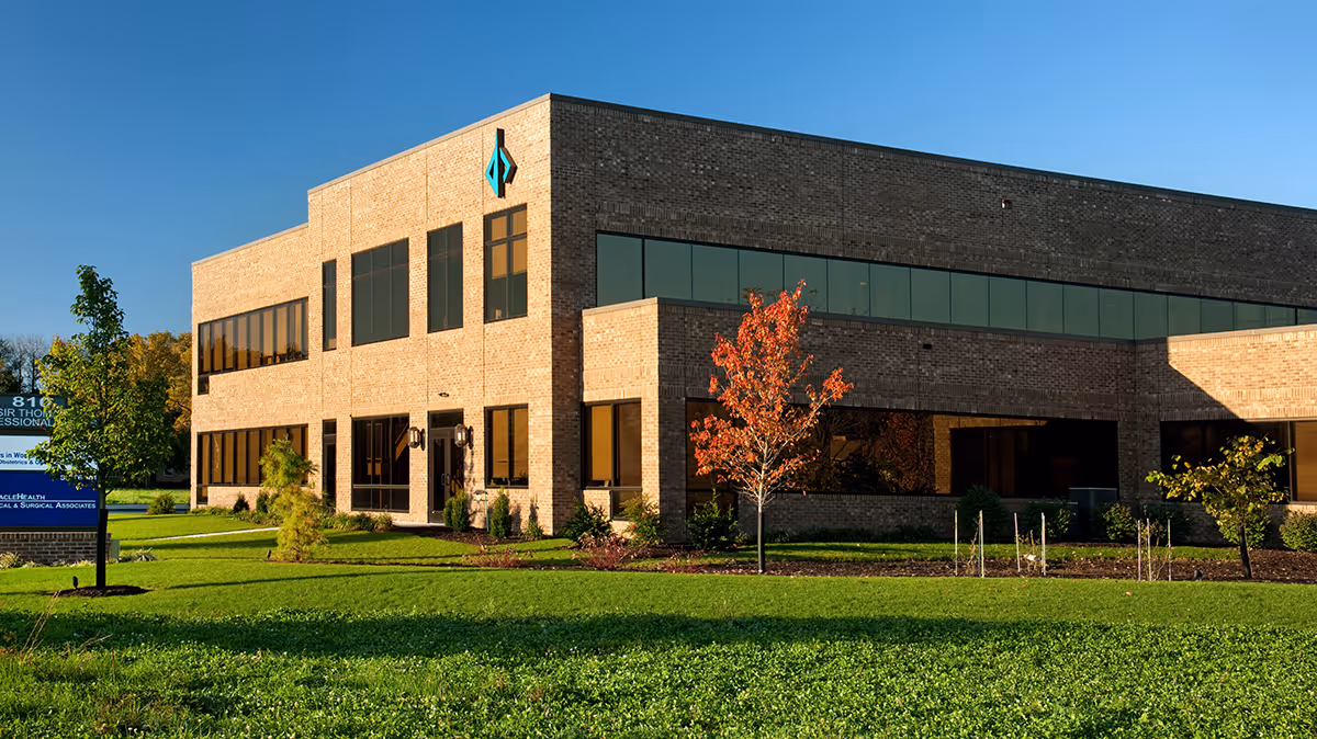 Modern brick medical facility with large glass windows and a manicured lawn.