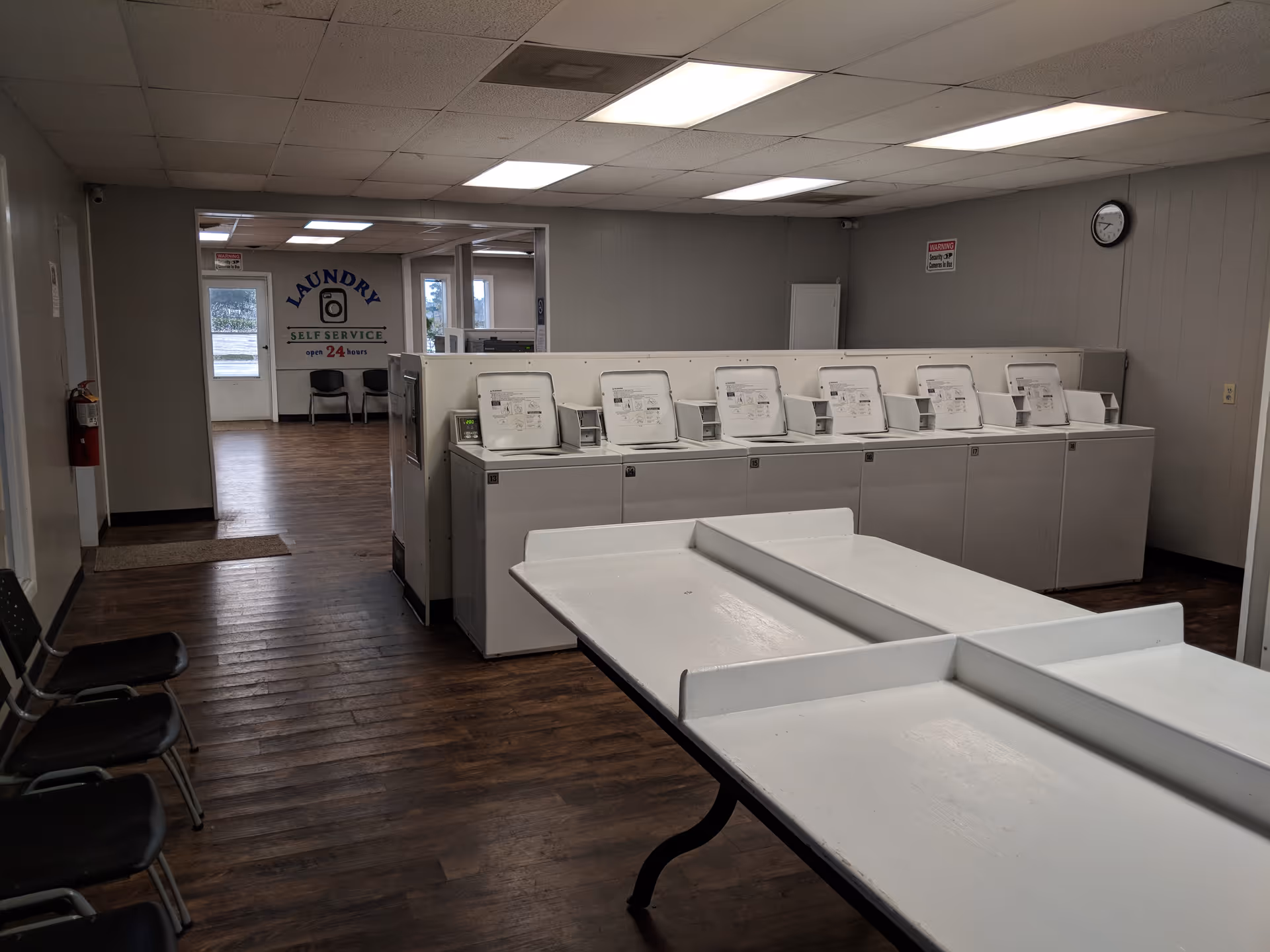 Senior facility laundry room with washing machines, a folding table, and chairs.