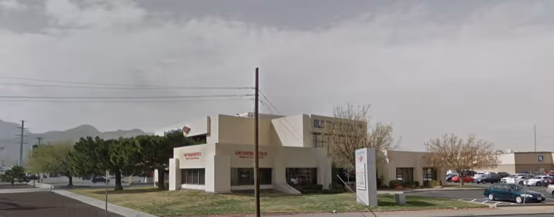 Beige, single-story building complex with signage and a parking lot in front