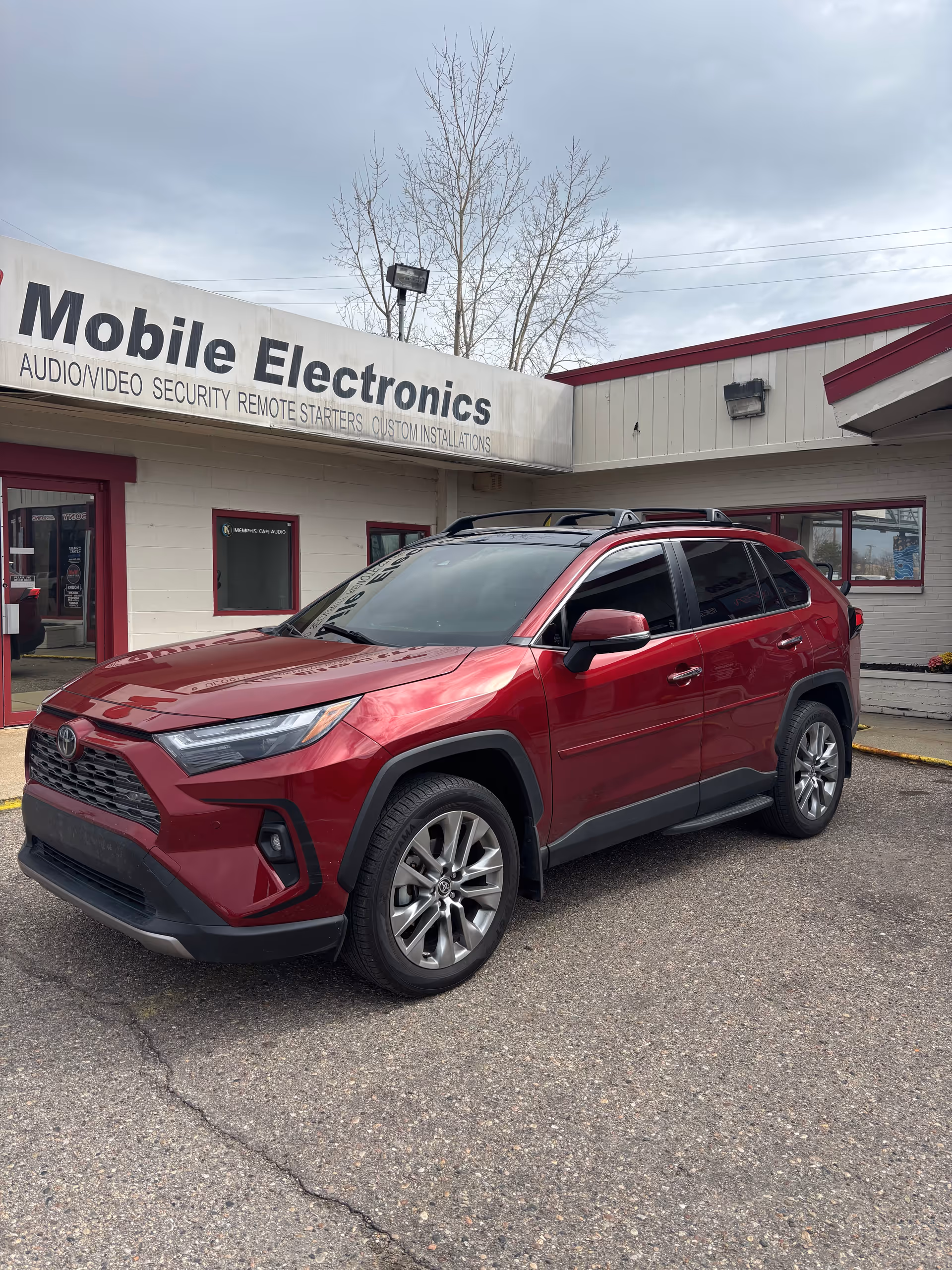 Red SUV parked outside a storefront with a sign reading Mobile Electronics.