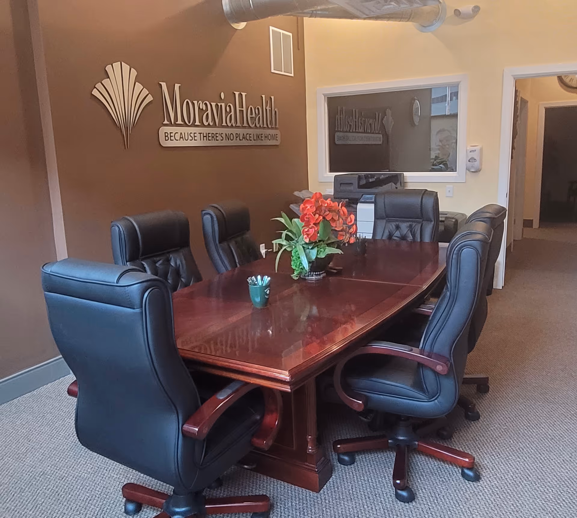 Moravia Health Harrisburg conference room featuring a long wooden table and black leather chairs.