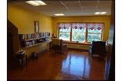 Cozy senior living lounge with chairs, bookshelves, and a large window.