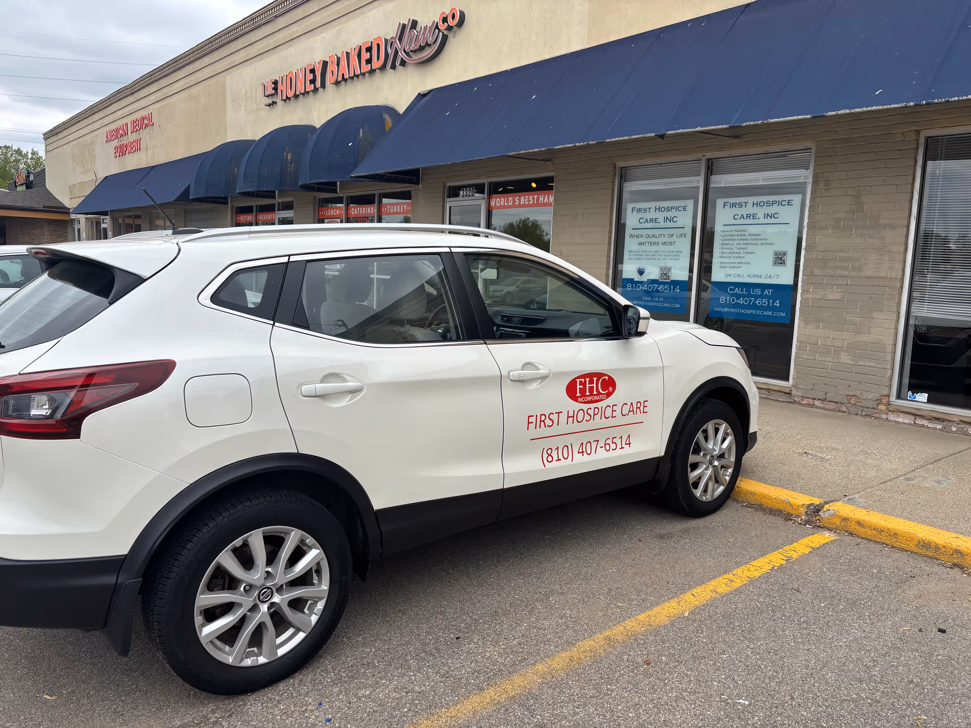 White SUV with First Hospice Care logo parked in front of a storefront.