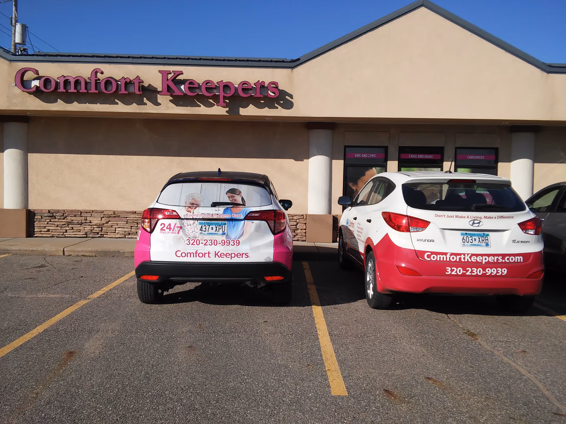 Front view of Comfort Keepers building with two branded cars in the parking lot.