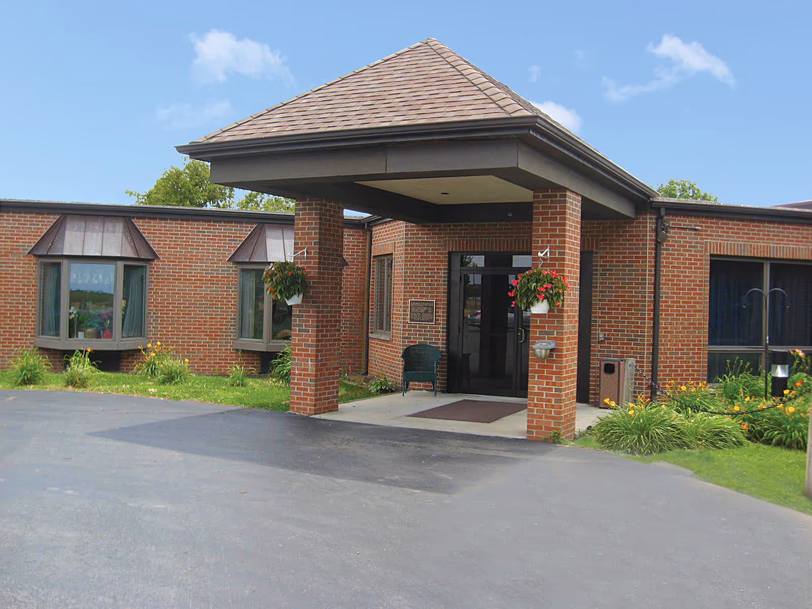 Brick Gillespie Health and Rehab Center entrance with a covered area and hanging flower baskets.
