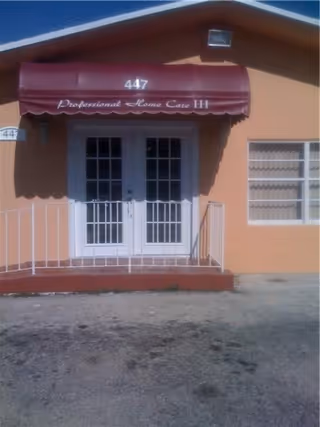 Front entrance of a peach-colored building with a maroon awning and double doors.