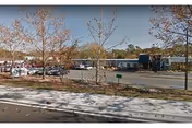 Exterior view of Eden Springs Nursing and Rehab with parked cars and trees.
