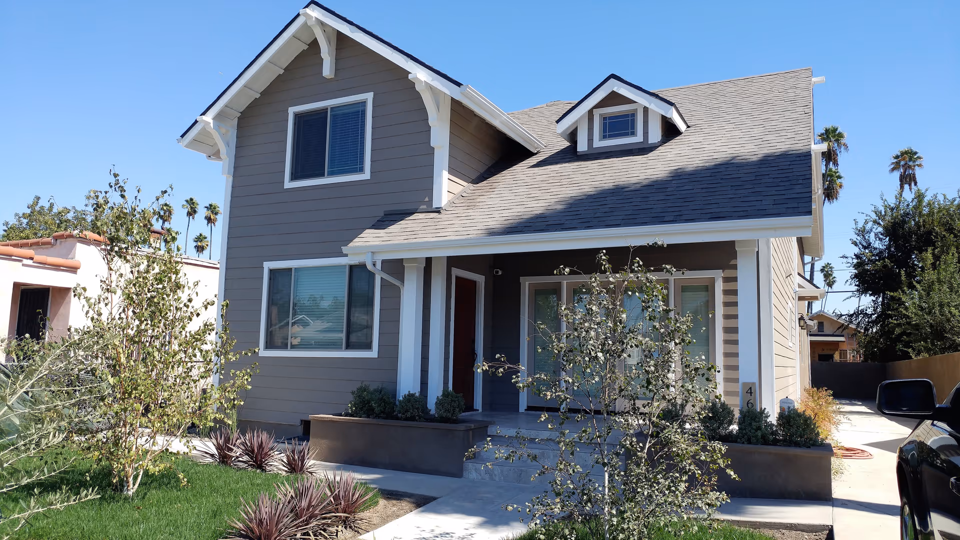 Front view of a modern gray two-story house with a small yard.