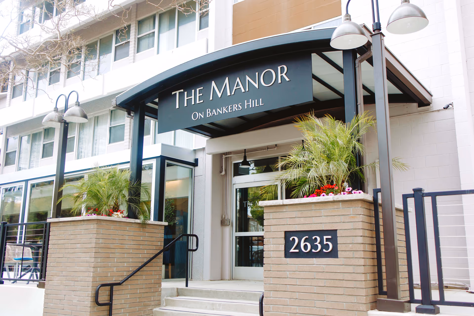 Exterior entrance of The Manor senior living facility with brick planters and address 2635.