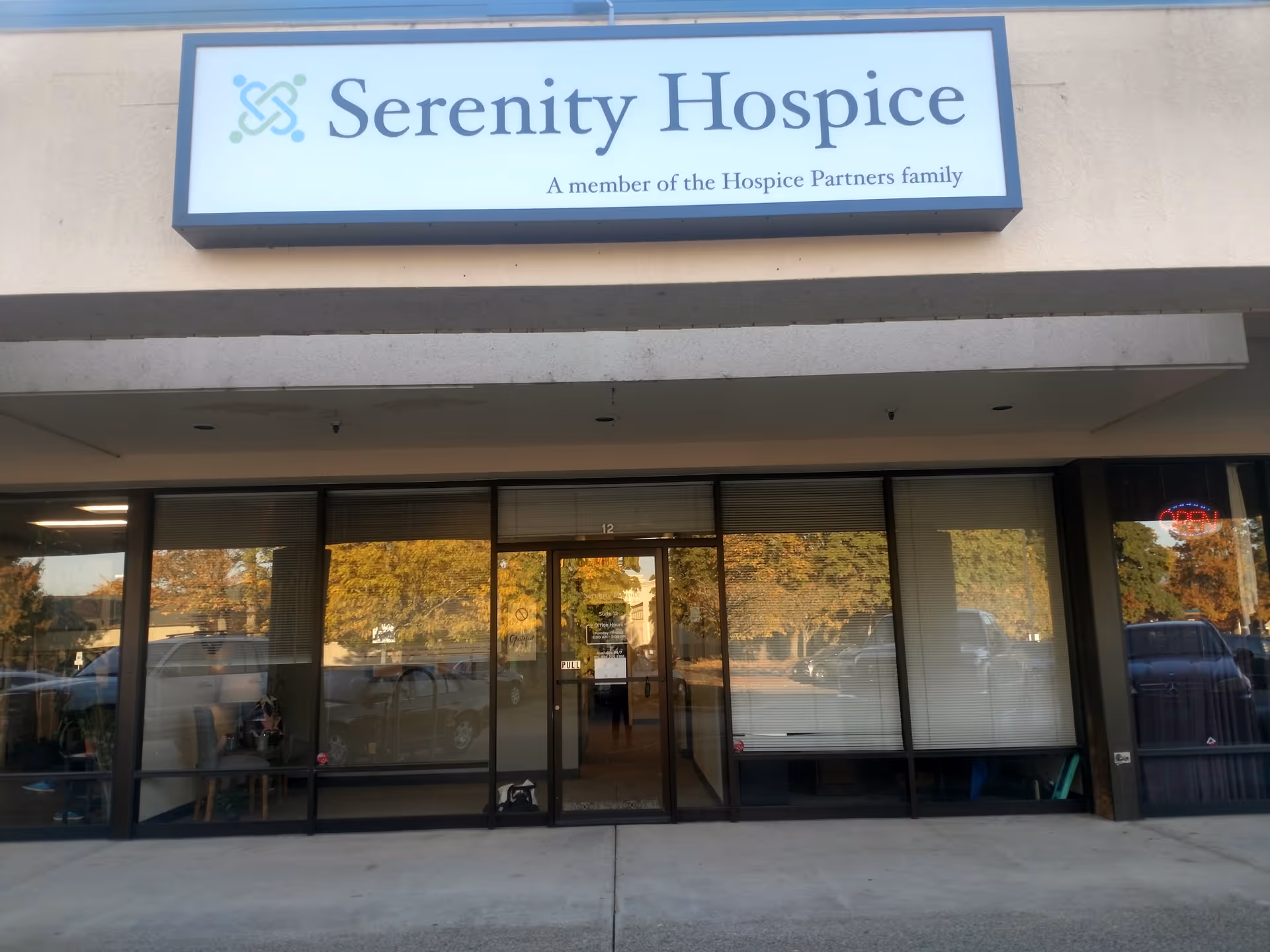 Front of Serenity Hospice building with large sign and glass storefront entrance.