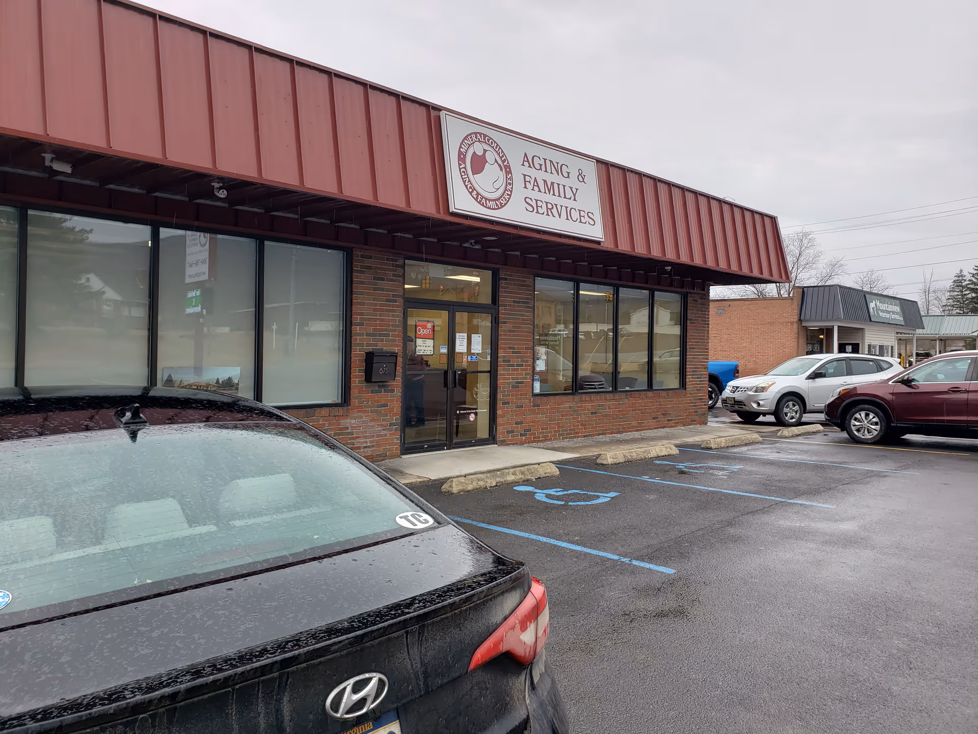 Brick building with red awning and Aging & Family Services sign in a parking lot.