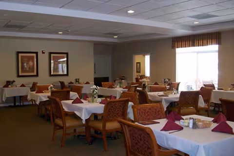 A communal dining room in a senior facility with tables set for meals.