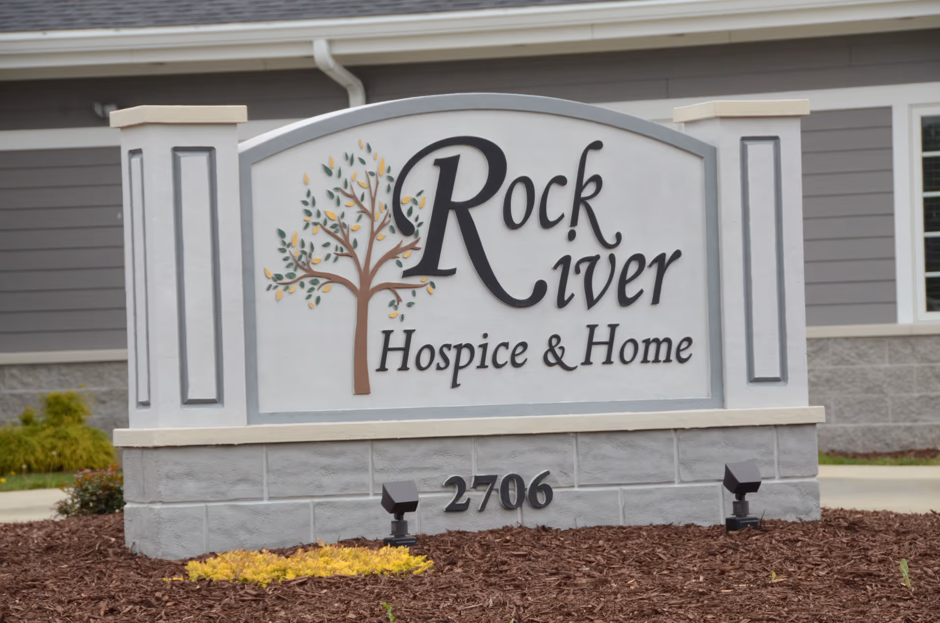 Rock River Hospice & Home sign displayed at landscaped front area of the facility exterior.