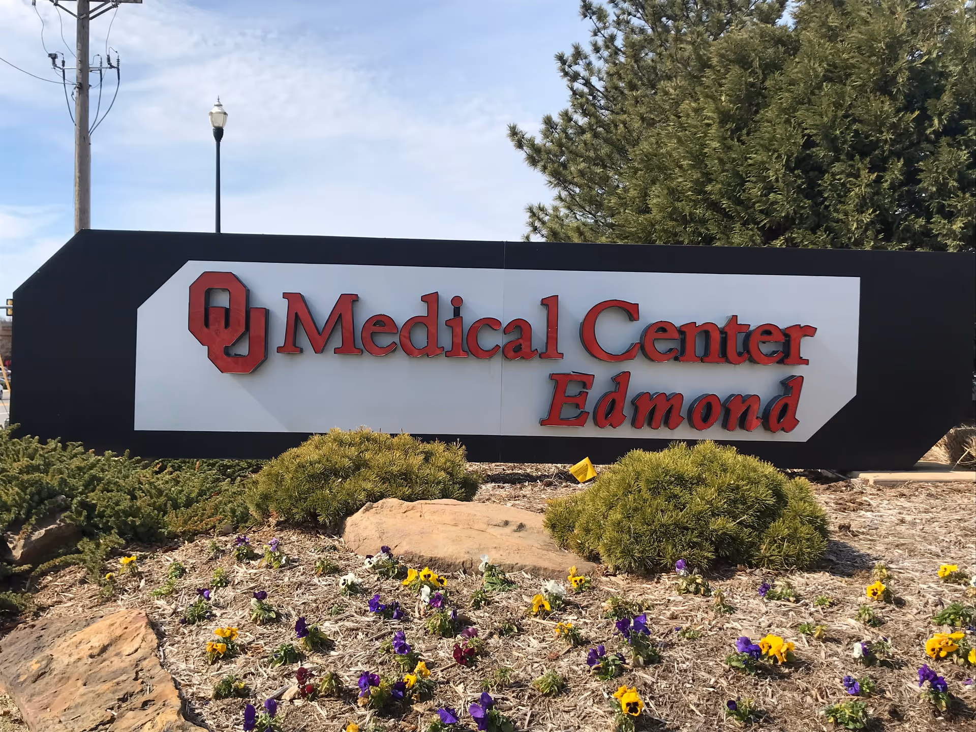 Large outdoor sign reading OU Medical Center Edmond with landscaping in front