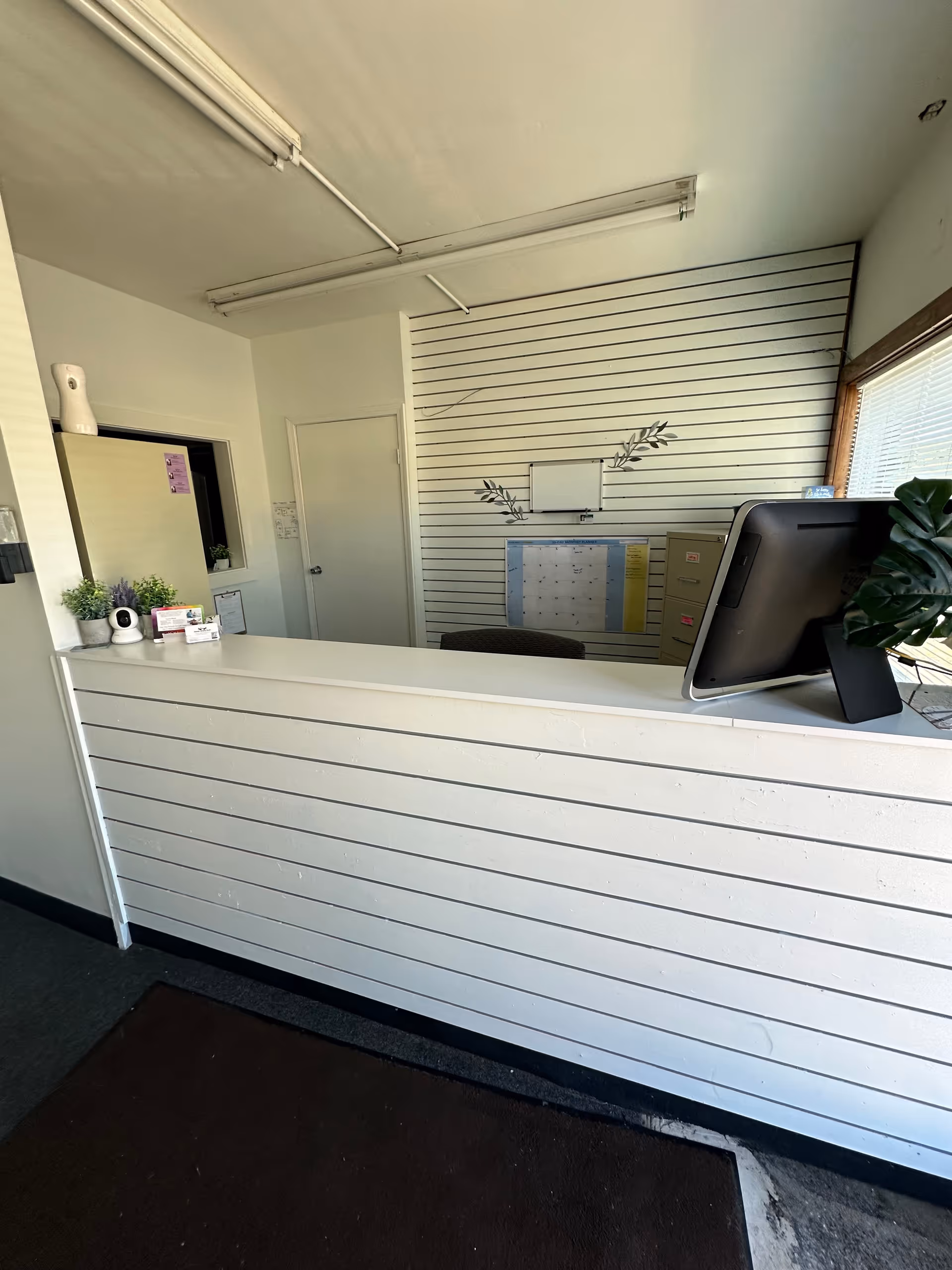 Reception desk in a bright facility lobby with computer monitor.