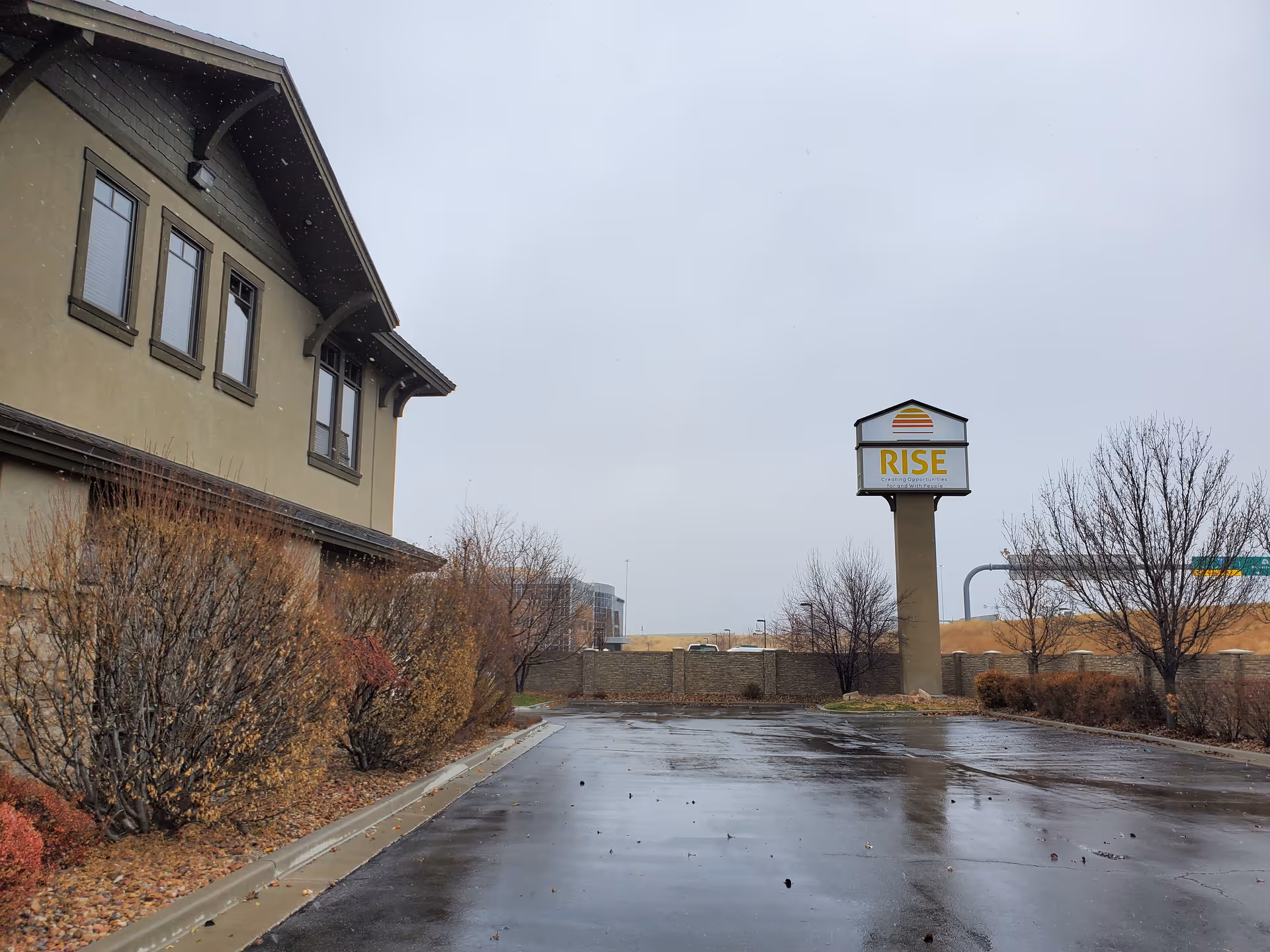 Exterior view of a Rise Services building with a tall sign beside a wet driveway.