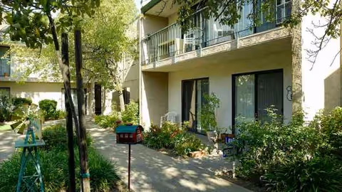 Exterior of an Atria senior living building with balconies, walkway, and landscaped courtyard.