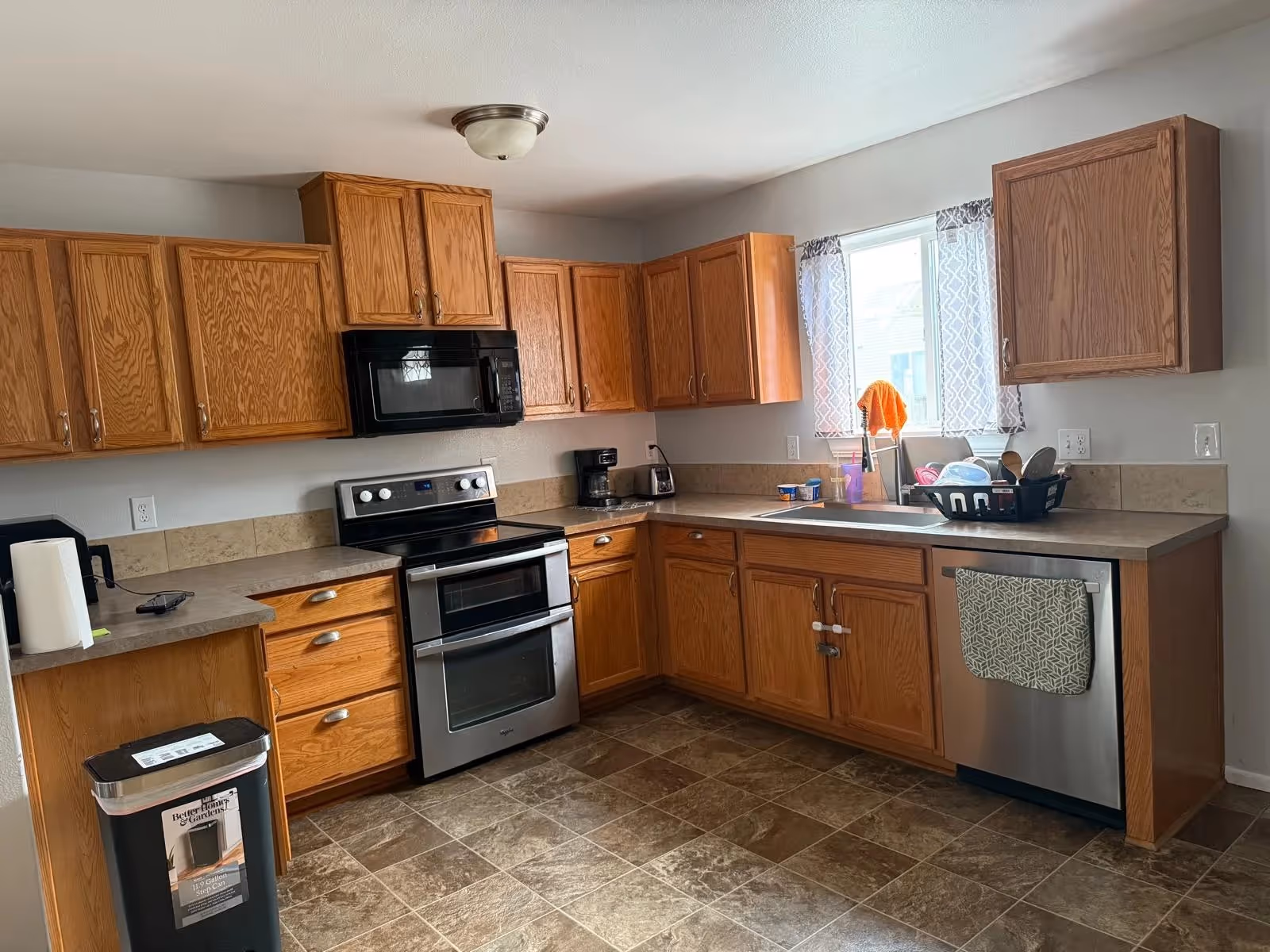 Cozy kitchen with wooden cabinets, stainless steel appliances, and a kitchen sink by a window.