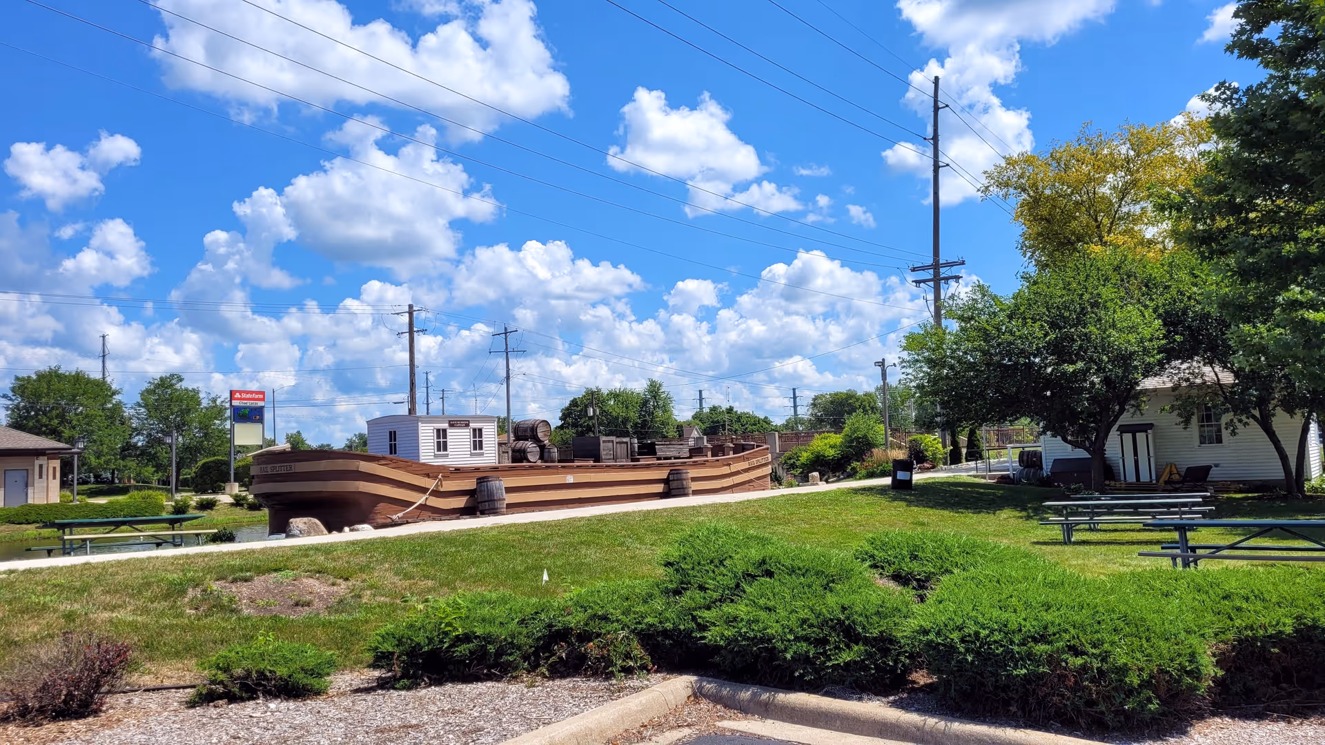 Outdoor park area featuring a large wooden ship sculpture, benches, and green lawns.