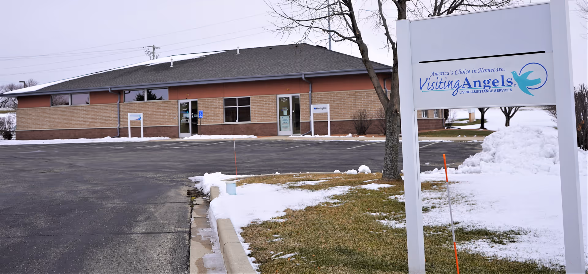 Exterior view of Visiting Angels facility with sign, brick walls, and snowy parking area.