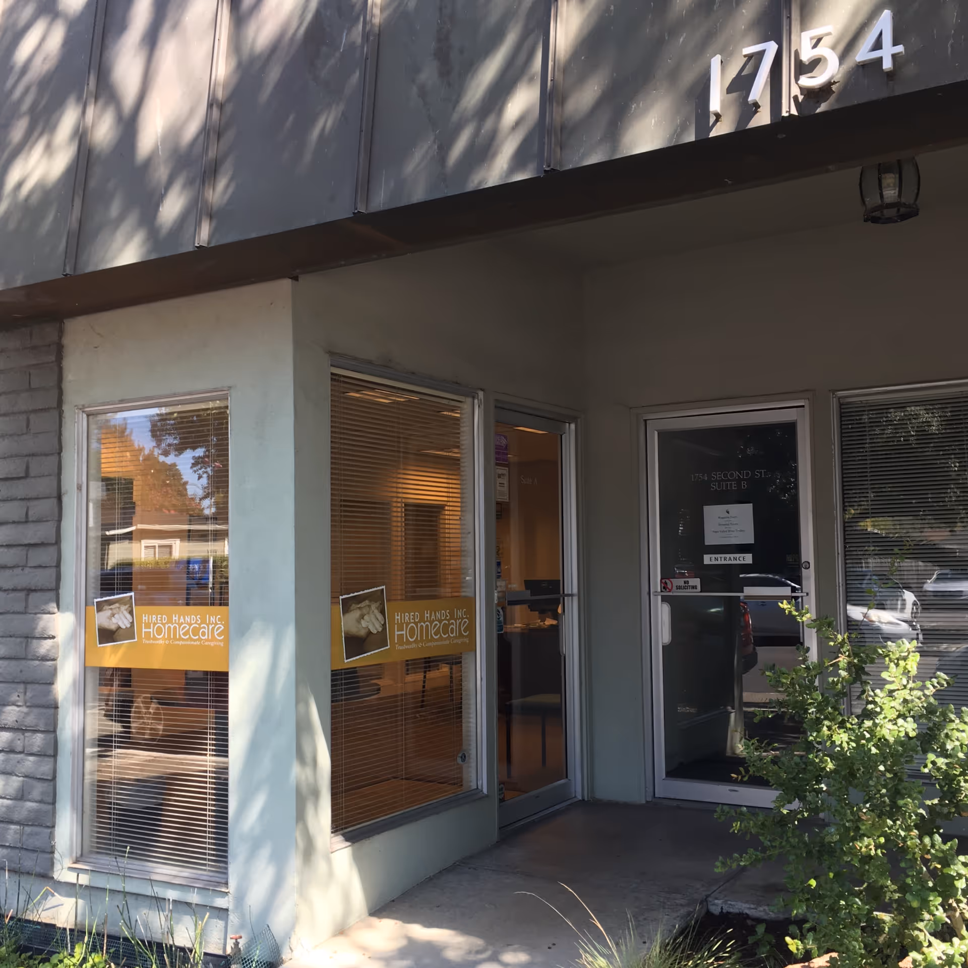 Exterior view of Hired Hands Homecare entrance with glass doors and signage.
