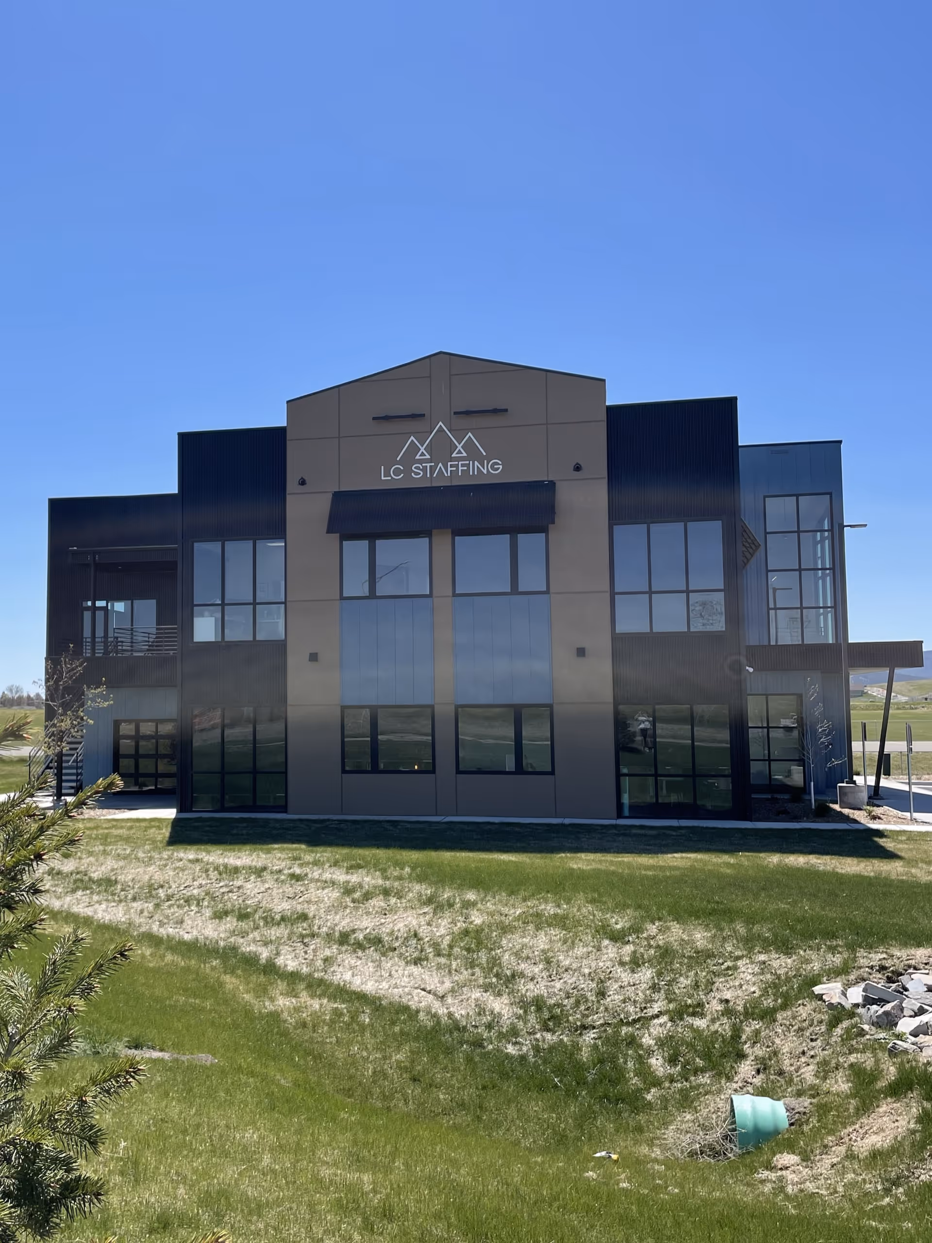 Modern two-story building with large glass windows and LC Staffing sign.