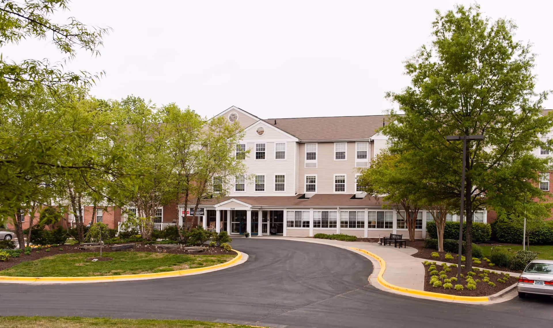A senior living facility with greenery and a circular driveway.