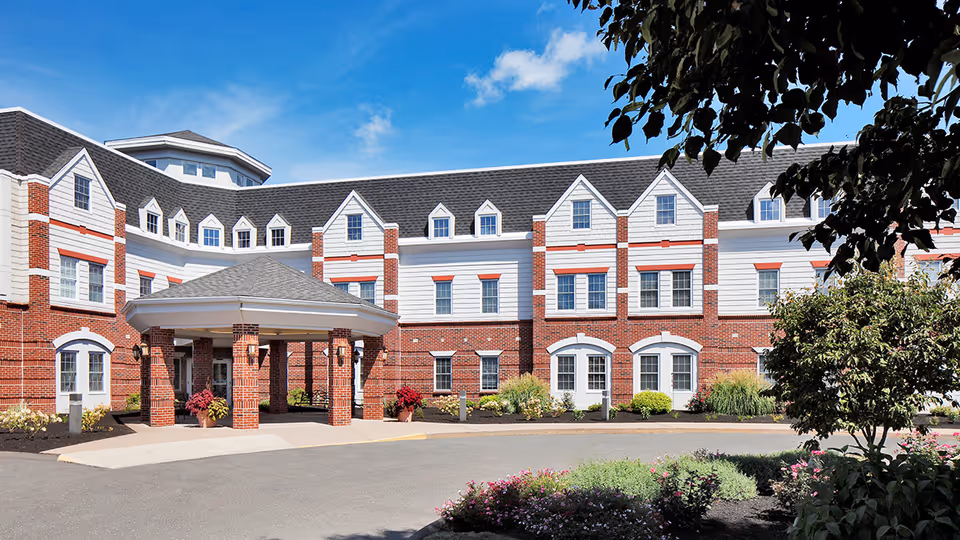 Exterior view of Addison Place at Glastonbury with brick building, porte-cochère, and landscaping.