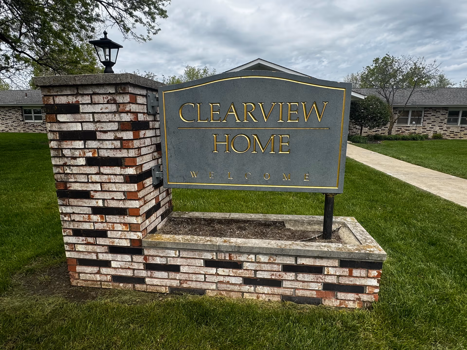 A brick-and-stone sign with lamp reads Clearview Home on a green lawn.