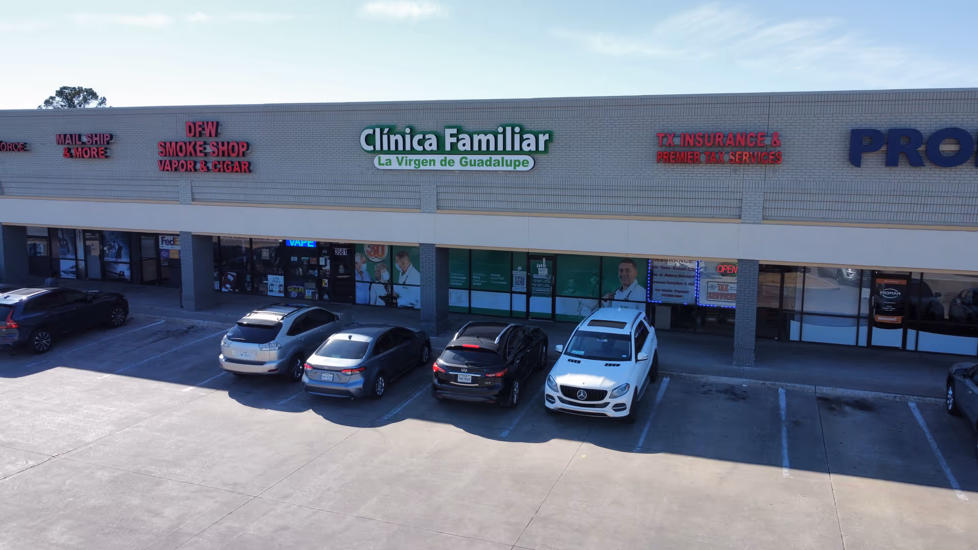 Exterior strip mall facade with Clinica Familiar La Virgen de Guadalupe sign and parked cars.