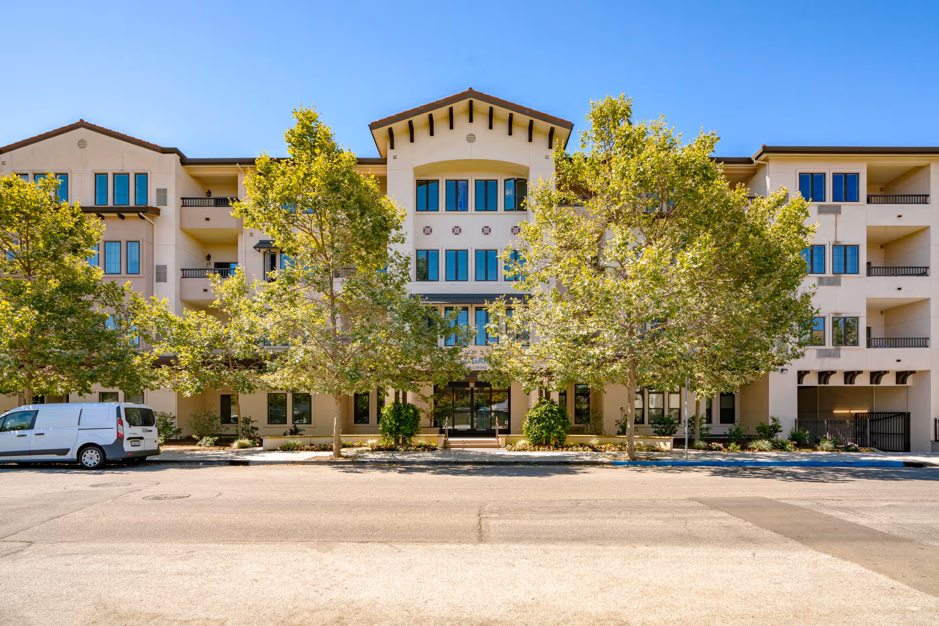 Senior living building exterior with trees and a street in front