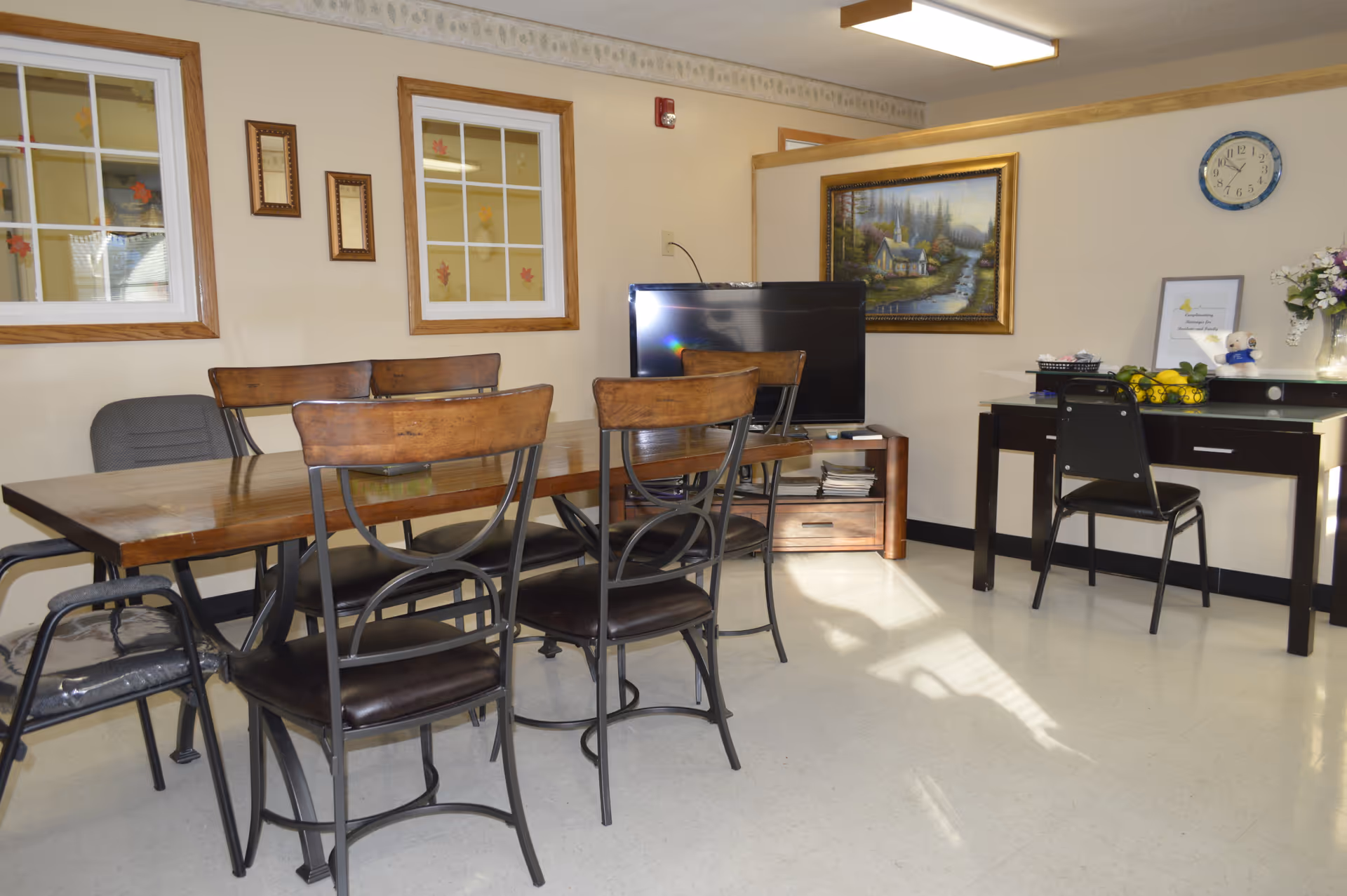 Wood dining table with chairs in a communal living area, TV and desk against walls.