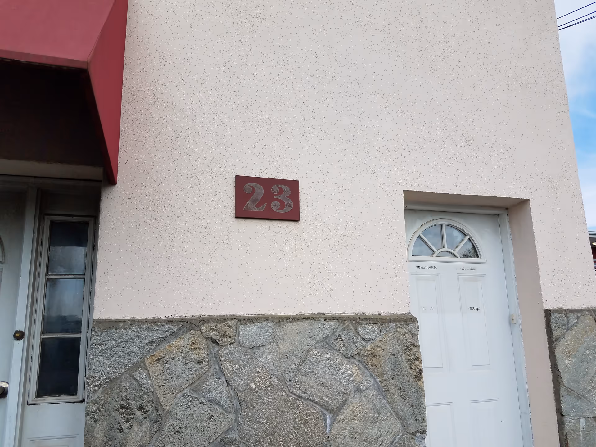 Exterior view of a building entrance with a white door and stone base.