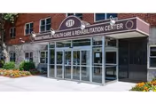 Exterior view of Manhattanville Health Care Center entrance with glass doors and maroon signage.