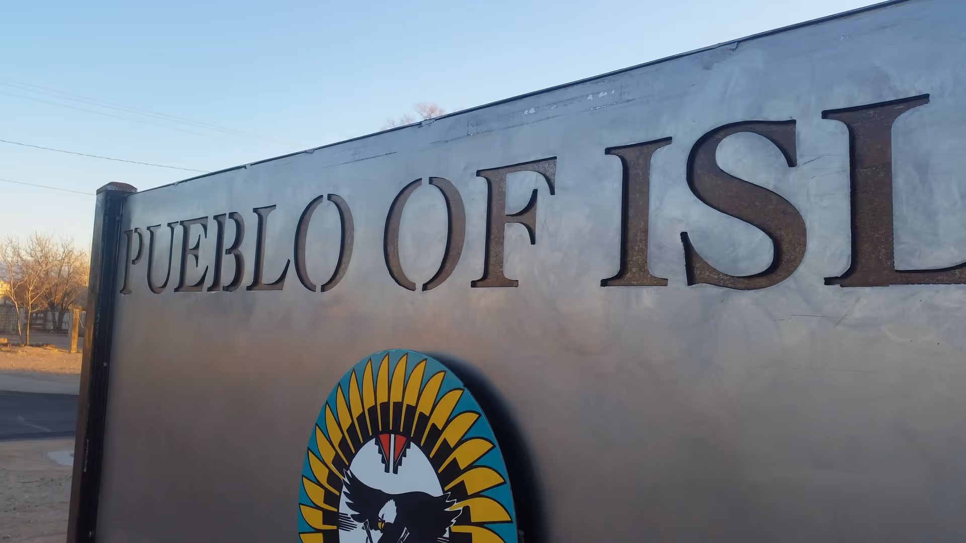 Exterior sign reading Pueblo of Isleta Elder Center on a metal wall with emblem.