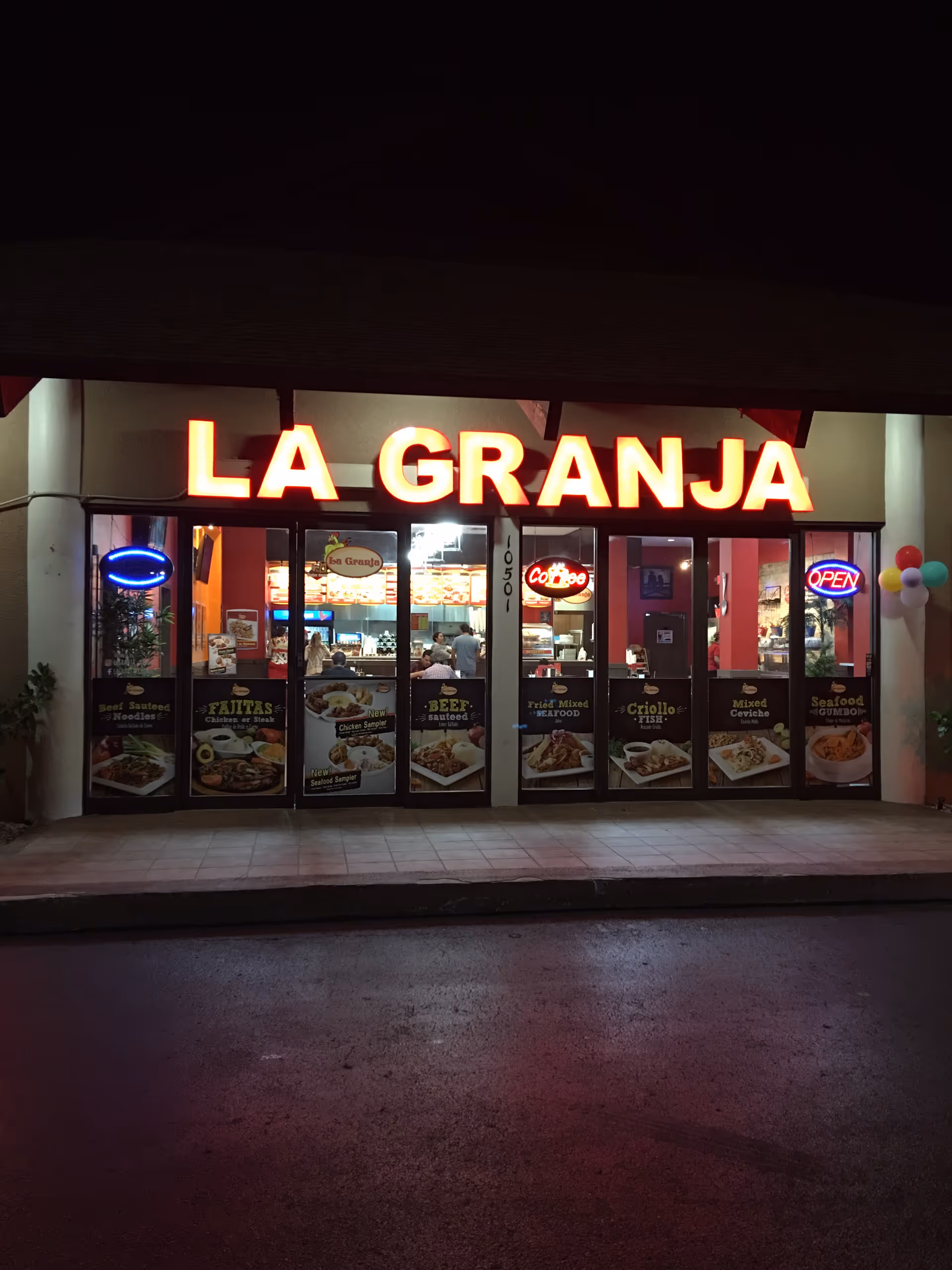 Nighttime storefront shows LA GRANJA restaurant with illuminated sign and posters.