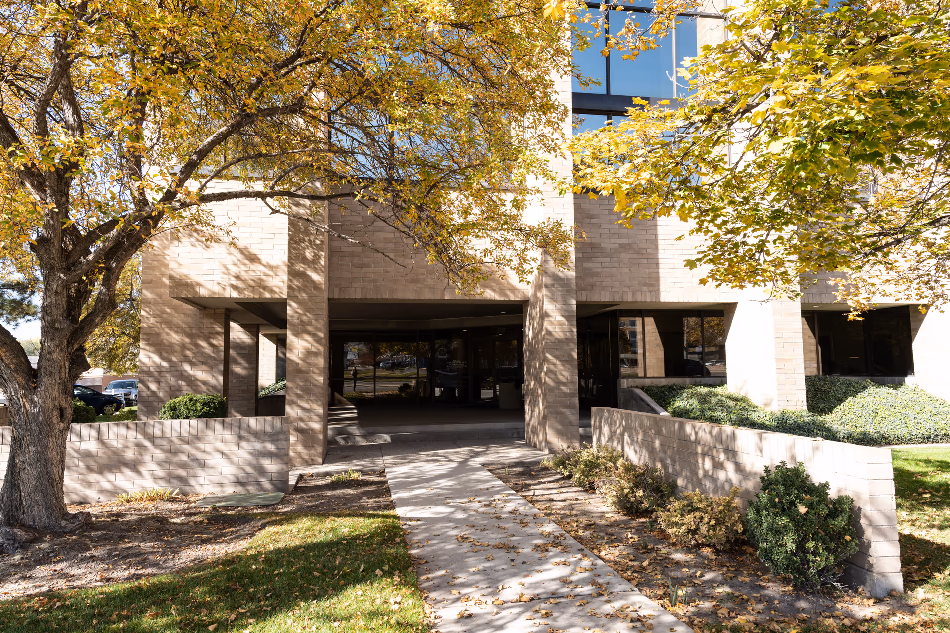 Front entrance of a brick building with trees and a walkway.