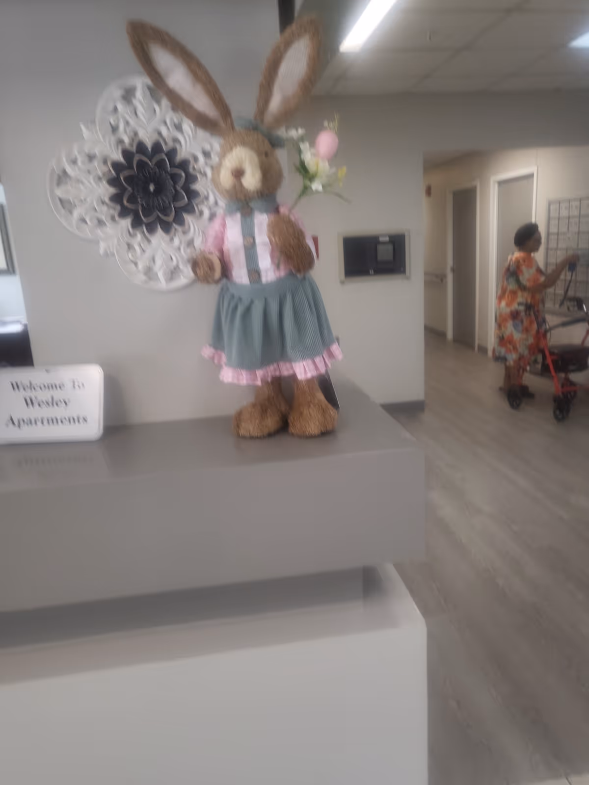 Interior lobby with an Easter bunny decor on a counter and a resident using a walker