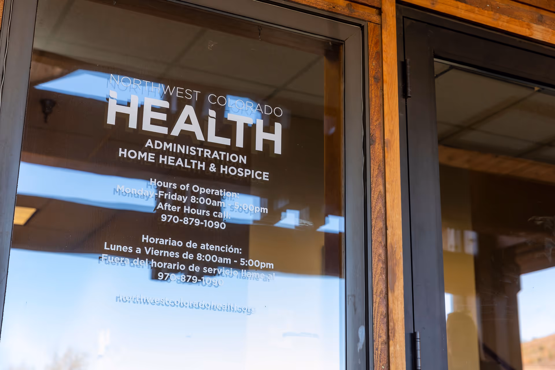 Glass entrance door with Northwest Colorado Health logo and hours printed on it.