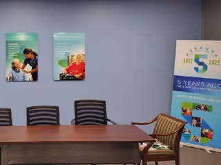 Conference table and chairs sit against a blue wall with an Aveanna banner.